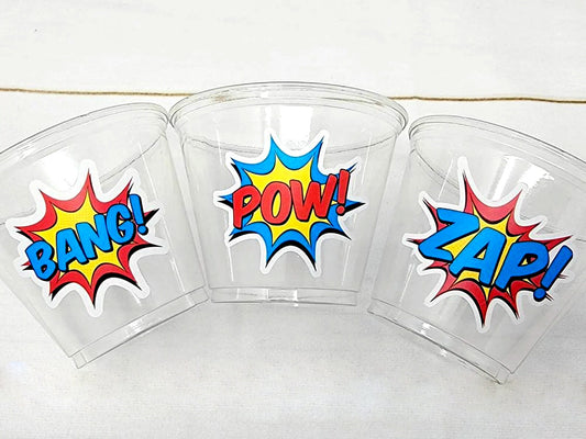 SUPERHERO PARTY CUPS - Superhero Cups Superhero Birthday Superhero Party Superhero Decorations Superhero Party Favors Superhero Decorations
May include: Three clear plastic cups with red, yellow, and blue comic book style stickers. The stickers have the words 'Bang!' 'Pow!' and 'Zap!' on them.