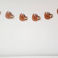 May include: A brown sloth garland with five sloths hanging from a white string. The sloths are facing to the right and have black eyes and noses.