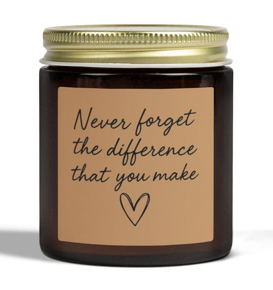 May include: A brown glass jar candle with a gold lid. The label is tan with the text "Never forget the difference that you make" and a heart symbol. The candle is likely scented.