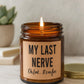May include: A lit brown glass jar candle with a tan label. The label reads "MY LAST NERVE" above "Oh Look... It's on fire" in black text. A gold lid sits next to the candle. A small succulent plant is in the background.