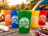 May include: A set of five colorful plastic stadium cups in orange, blue, green, yellow, and red. Each cup features a white circular graphic with a campfire illustration, pine trees, and the text "Fires, Friends, Fun, Camping Crew".